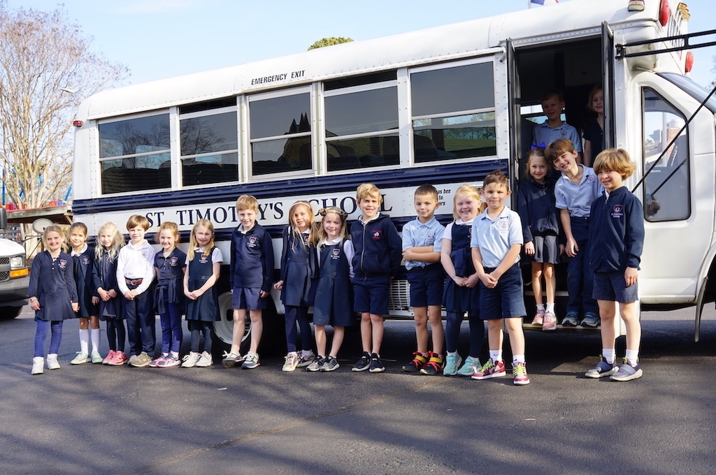 Students smiling in front of our new St. Timothy's school bus