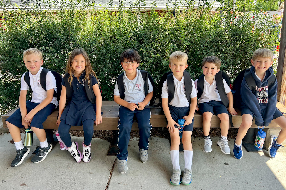 St. Timothy's students sitting on a bench at the end of a school day