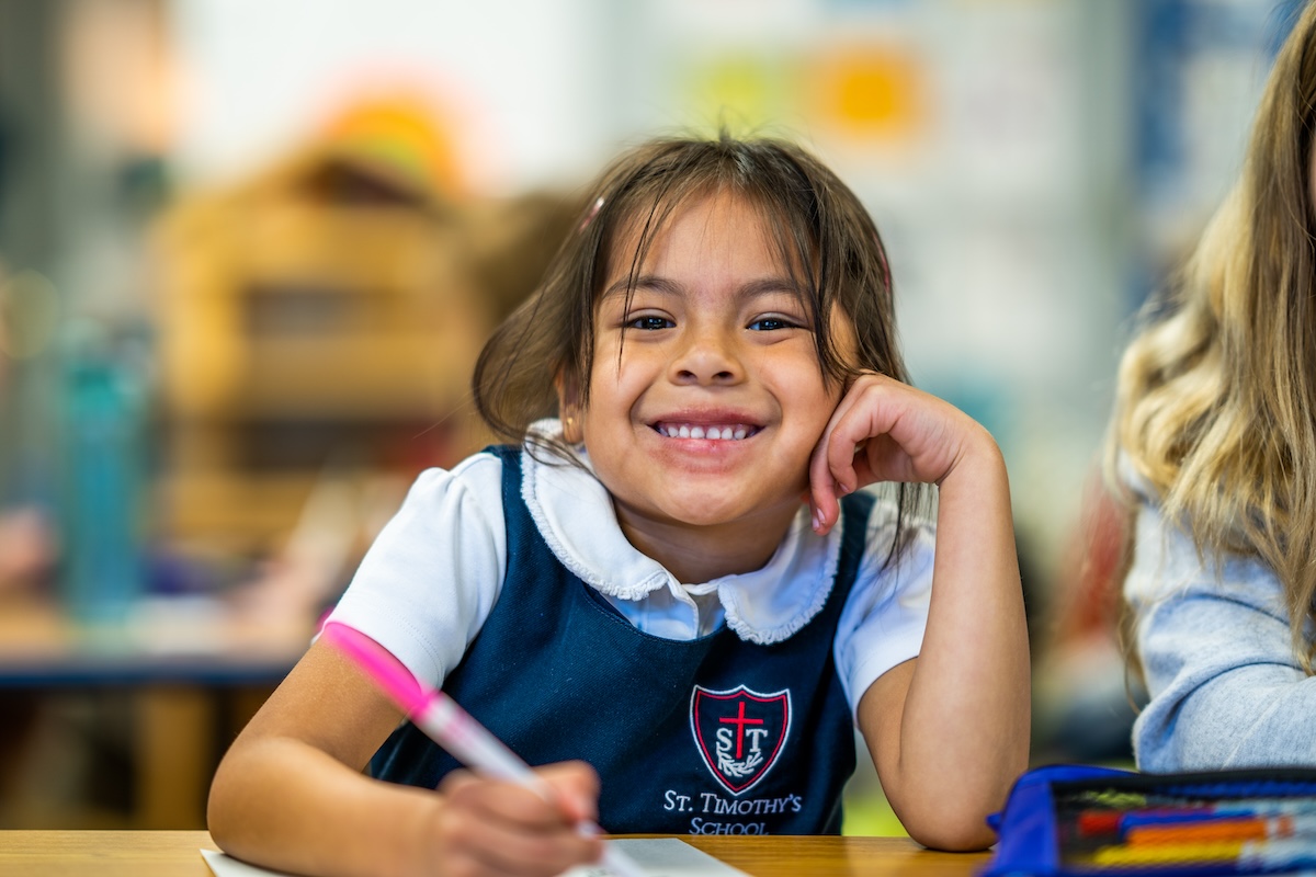Lower School student smiling while drawing in class
